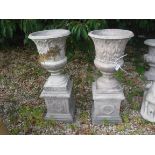 A pair of composite stone urns with acanthus leaf decoration on stepped square bases 94 cm high