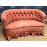 An early 20th Century buttoned upholstered canape of curved form, raised on turned feet,