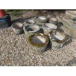 A collection of eight composite stone circular garden urns, varying sizes,