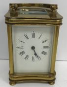 An early 20th Century lacquered brass cased carriage clock of waisted rectangular form raised on