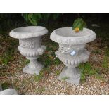 A pair of composite stone urns of campanula form with mask head handles 65 cm high