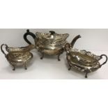 A George V silver three-piece tea set with pierced rim over an oval bellied body,