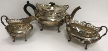 A George V silver three-piece tea set with pierced rim over an oval bellied body,