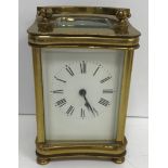An early 20th Century lacquered brass cased carriage clock of waisted rectangular form raised on