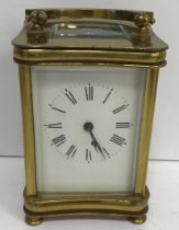 An early 20th Century lacquered brass cased carriage clock of waisted rectangular form raised on