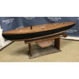 A vintage painted wood pond yacht with metal rudder and keel on a pine stand,