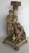 An early 20th Century Royal Dux figure group lamp base as a standing figure with vase and seated