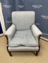 An Edwardian upholstered show frame scroll arm chair on turned and fluted tapering front legs to