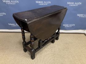 An oak oval gate leg drop leaf dining table in the 17th Century manner on turned supports to carved