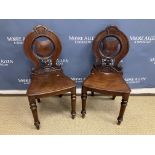A pair of Victorian mahogany panel seated hall chairs with pierced shield-shaped back splat on