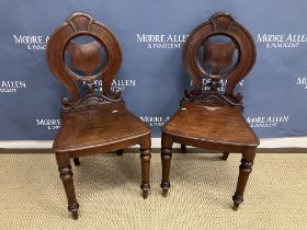 A pair of Victorian mahogany panel seated hall chairs with pierced shield-shaped back splat on