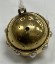 A late Victorian yellow metal and seed pearl mounted celestial globe pendant set with stanhope