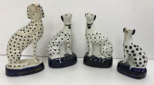 A pair of Staffordshire dalmatian figures on a dark blue oval base 15 cm high together with another