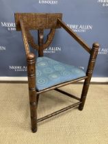 An oak corner chair in the 17th Century style with carved back rail above a panel seat on turned