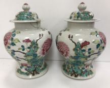 A pair of 19th Century Chinese famille rose vases and covers,