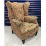 A Victorian upholstered wing back scroll arm chair on turned and reeded mahogany front legs to