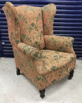 A Victorian upholstered wing back scroll arm chair on turned and reeded mahogany front legs to