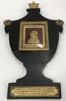 A George III black lacquered papier-mâché urn shaped plaque with crowned finial and suspension loop,