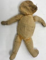 A dark gold plush wood wool filled bear of small proportions with hump back (unnamed) 27 cm long