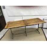 An oak plank top dining table with cleated ends on an earlier painted cast iron triple pillar base