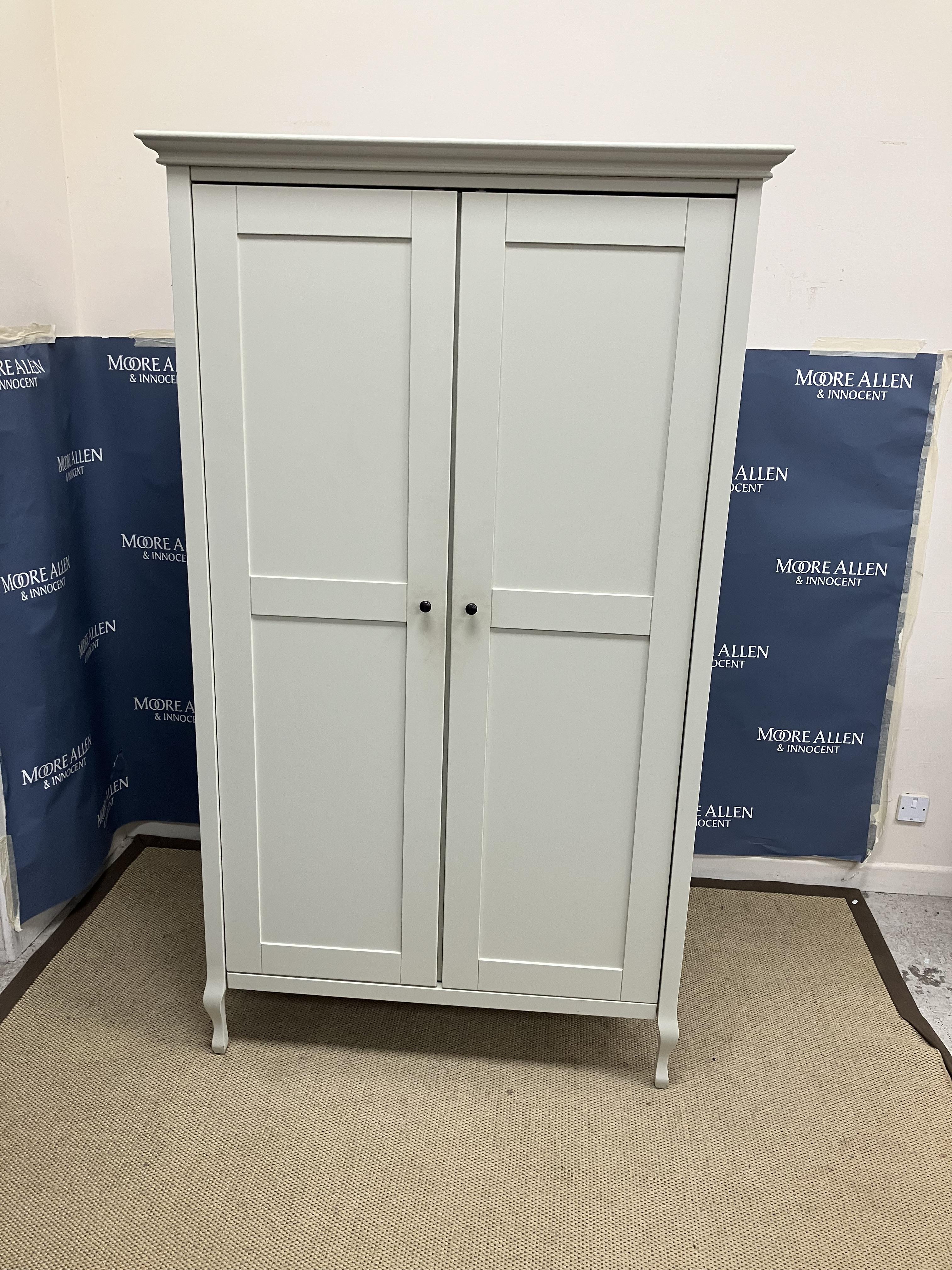 A Laura Ashley painted two door wardrobe opening to reveal a shelf and hanging space,