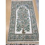 A crewel work panel depicting tree and birds in blue and teal on a cream and blue ground,