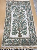 A crewel work panel depicting tree and birds in blue and teal on a cream and blue ground,