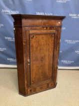 A George III North Country English oak hanging corner cupboard the moulded cornice over a cross