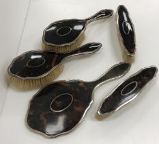 A collection of silver backed hair brushes and mirrors, some with tortoiseshell mounts,