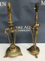 Two gilt brass table lamps in the Empire style, both with ram's head and hoof decoration,
