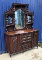 A late Victorian carved walnut side board with mirrored super structure over three central drawers