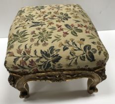 Two near matching Victorian carved giltwood framed footstools with floral decorated upholstery