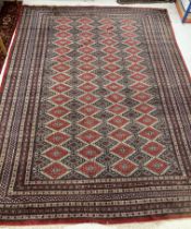 A Bokhara rug, the central panel set with repeating rows of lozenge shaped medallions on a cream,