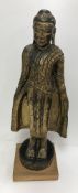 A 19th Century Tibetan carved giltwood figure of the Buddha in long jacket, his hands at his sides,