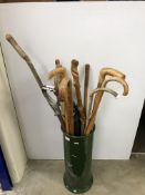 A pottery stick stand containing various walking sticks, canes, etc,