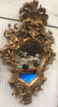 A modern gilt framed wall mirror in the Continental Rococo taste with foliate scrollwork pediment