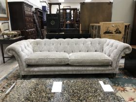 A modern silvered velvet style upholstered buttoned scroll arm sofa on turned mahogany front legs