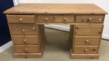 A modern pine kneehole desk, the plain top above three frieze drawers on two banks of three drawers,