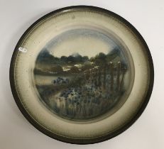 A Studio pottery charger decorated with woodland landscape scene to the centre field within a
