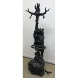 A 19th Century Black Forest carved and stained wood stick stand in the form of a bear clutching a