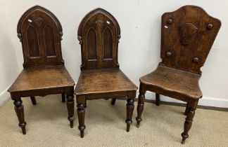 A pair of Victorian oak panel seat hall chairs with arched twin panelled backs in the Gothic