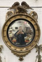 A Regency carved giltwood and gesso framed circular wall mirror with spreadeagle surmount,