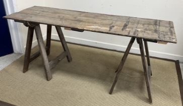 A 20th Century pine trestle table, the three plank top on two folding A frame bases,