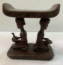 An African carved hardwood head rest or pillow with figural decoration of kneeling figure with