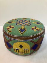 A Yoruba Royal foot cushion with all over mask, flower and love heart motifs, 30 cm diameter x 17.