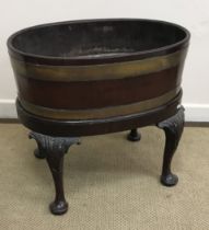 A George III mahogany and brass bound wine cooler of oval coopered form,