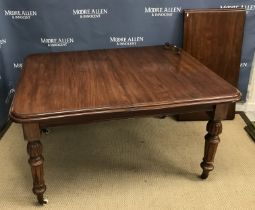 A walnut rectangular extending dining table with single extra leaf raised on turned,