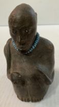 A Tanzanian terracotta figure of a seated man with snake and turquoise necklace and bead inset eyes