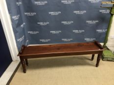 A mahogany window seat in the Victorian manner, the plank top with moulded edge and scroll ends on