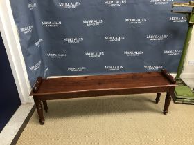 A mahogany window seat in the Victorian manner, the plank top with moulded edge and scroll ends on